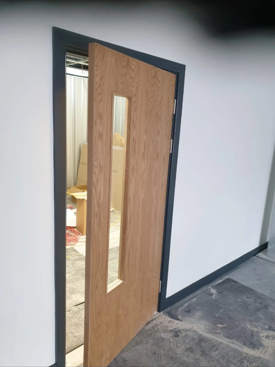 Vision-panel fire door hung in a dark painted frame